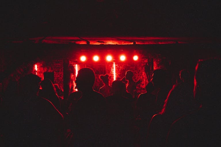 Dynamic crowd enjoying live music performance with intense red lighting on stage.