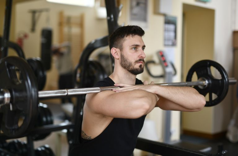 A focused man lifting weights indoors showcasing strength and concentration.