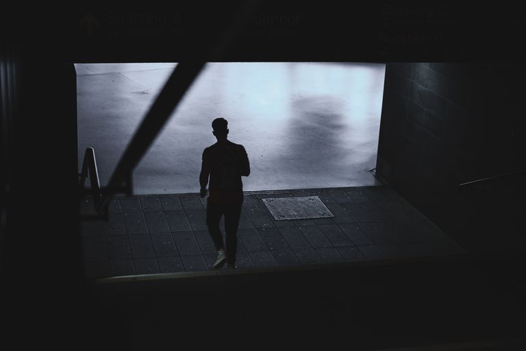 Artistic silhouette of a single person descending steps indoors, creating a dramatic and moody atmosphere.